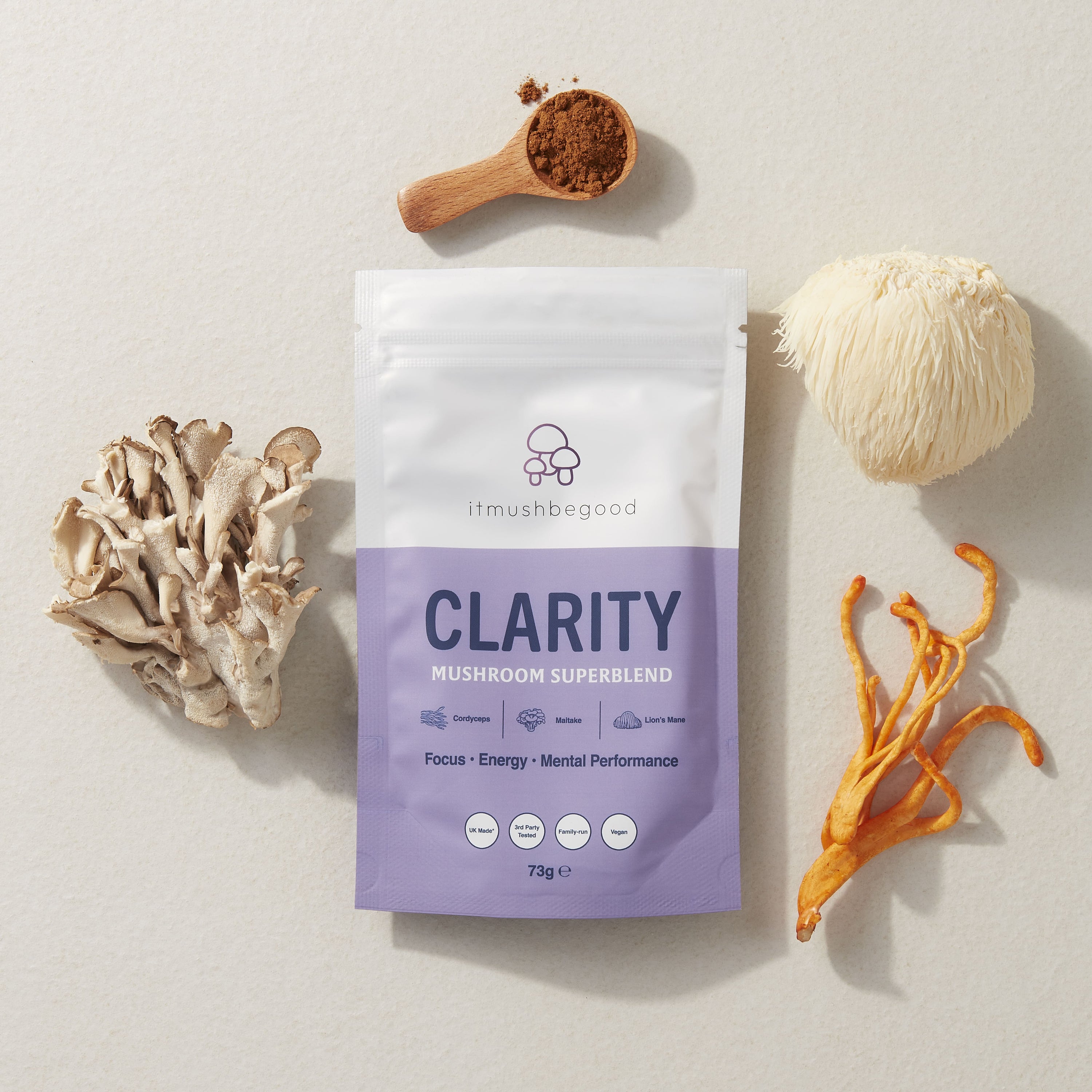 Clarity Sachet surrounded by functional mushrooms and the powder supplement in a wooden spoon